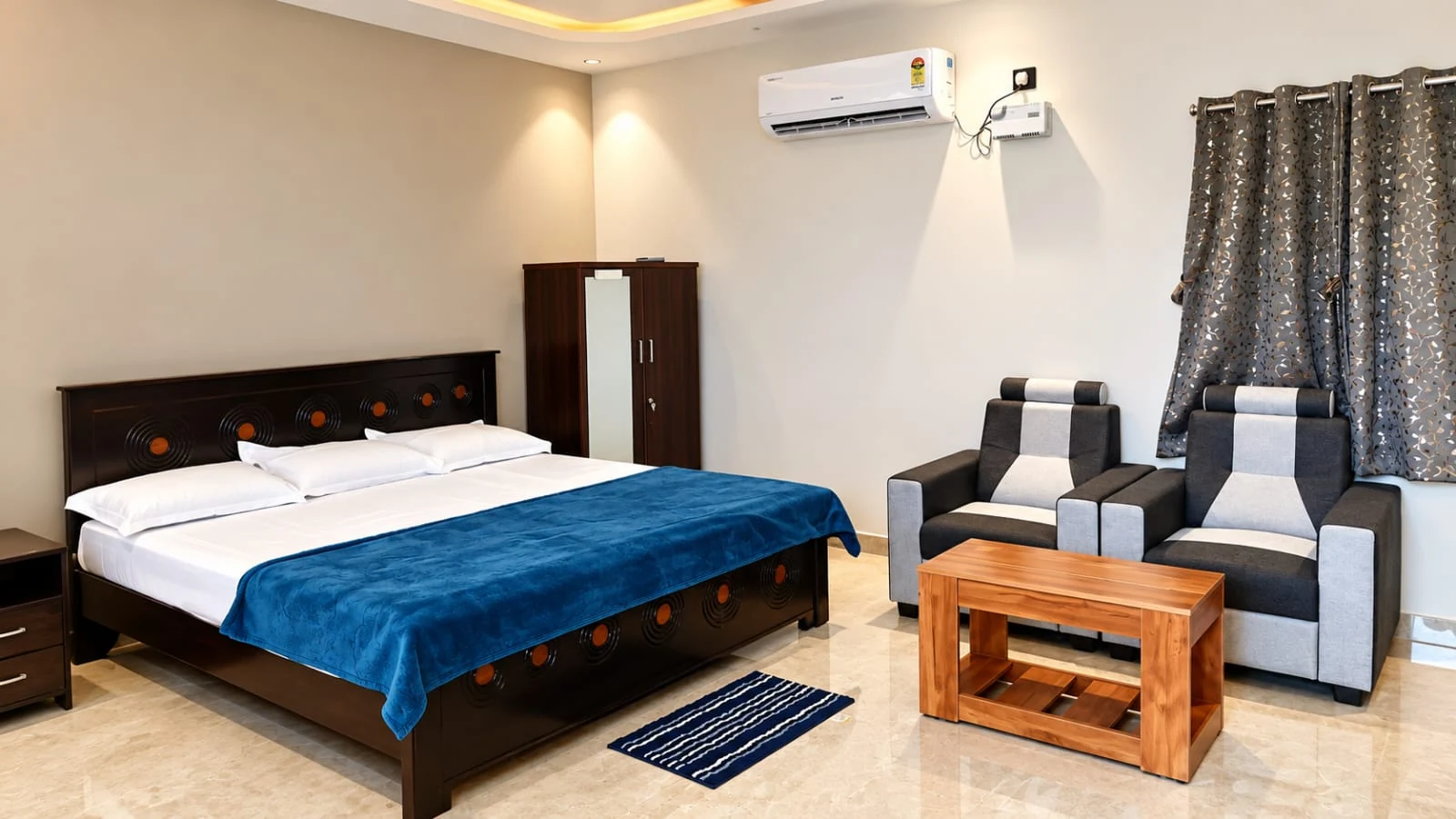 Actual guest room at AVULA’S RESORTS with double bed, air conditioner and armchair seating